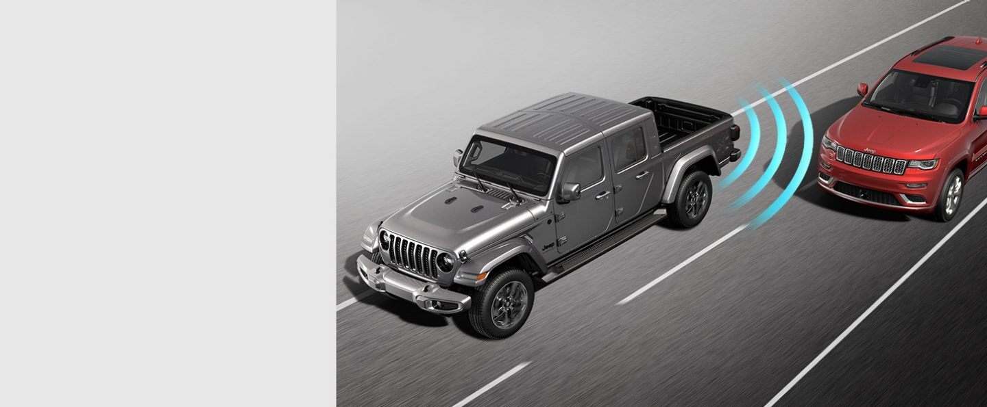 The 2021 Jeep Gladiator High Altitude with illustrated sensors monitoring the area behind the rear bumper, detecting a vehicle in the next lane.