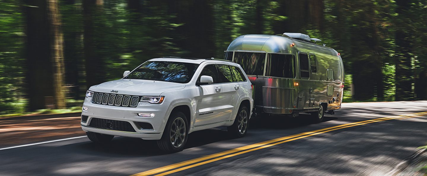 The 2021 Jeep Grand Cherokee Summit towing a trailer on a two-lane road.